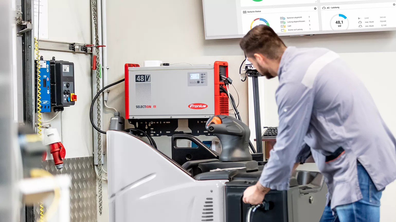 A man is connecting a forklift truck to a SelectION lithium-ion battery charger for charging.